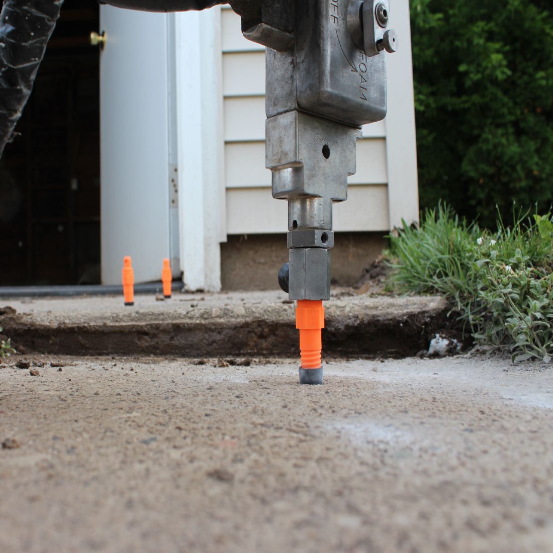 Uneven concrete slabs with polyurethane foam being injected through orange injector ports