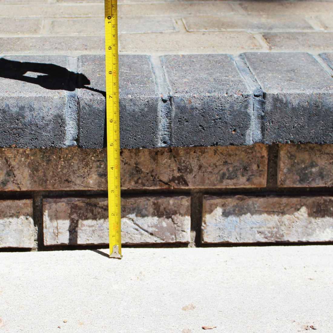 A measuring tape measuring a brick stair that is lowered